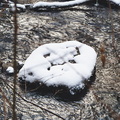 Snow lies on the rocks that lie in the river